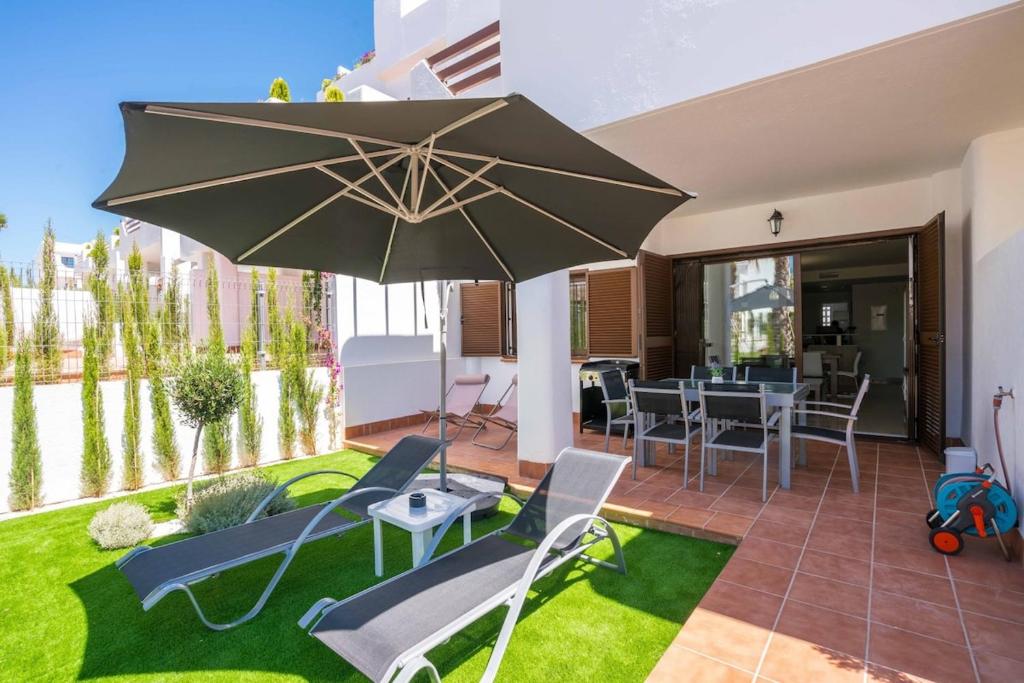 a patio with an umbrella and chairs and a table at Kaki in San Juan de los Terreros