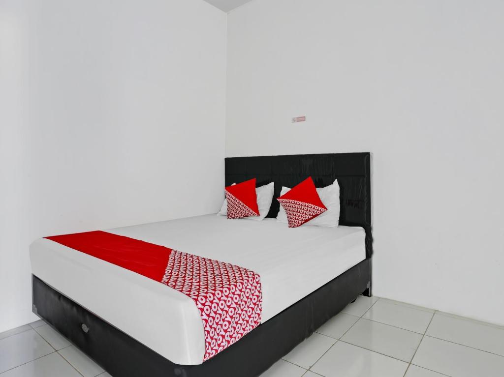 a bed with red and white pillows on it at SUPER OYO 90550 Good Sleep 3 Samarinda in Samarinda