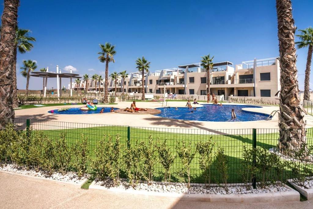 un complejo con dos piscinas con gente jugando en ellas en Apartment Claveles, en Orihuela Costa