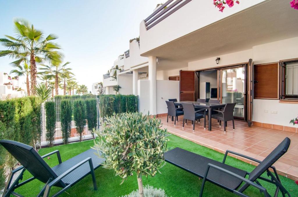 a patio with chairs and a table on a lawn at Mora in San Juan de los Terreros