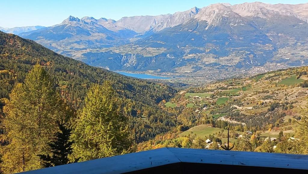 Elle offre une vue sur une vallée avec des montagnes et un lac. dans l'établissement Les écureuils du Méale, aux Orres