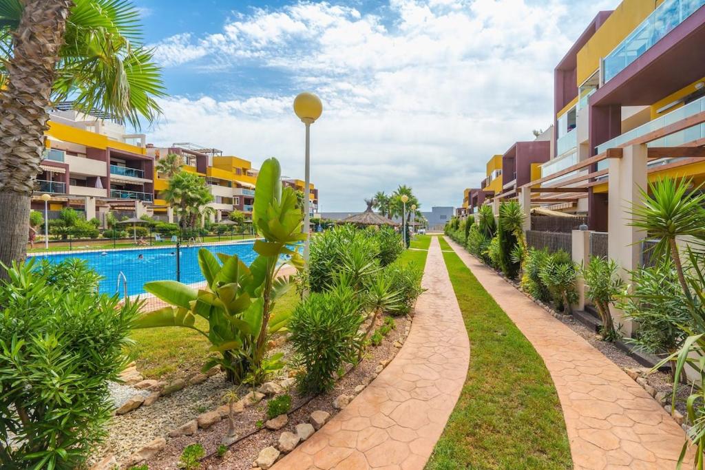 a walkway next to a resort with a swimming pool at El Bosque in Orihuela Costa