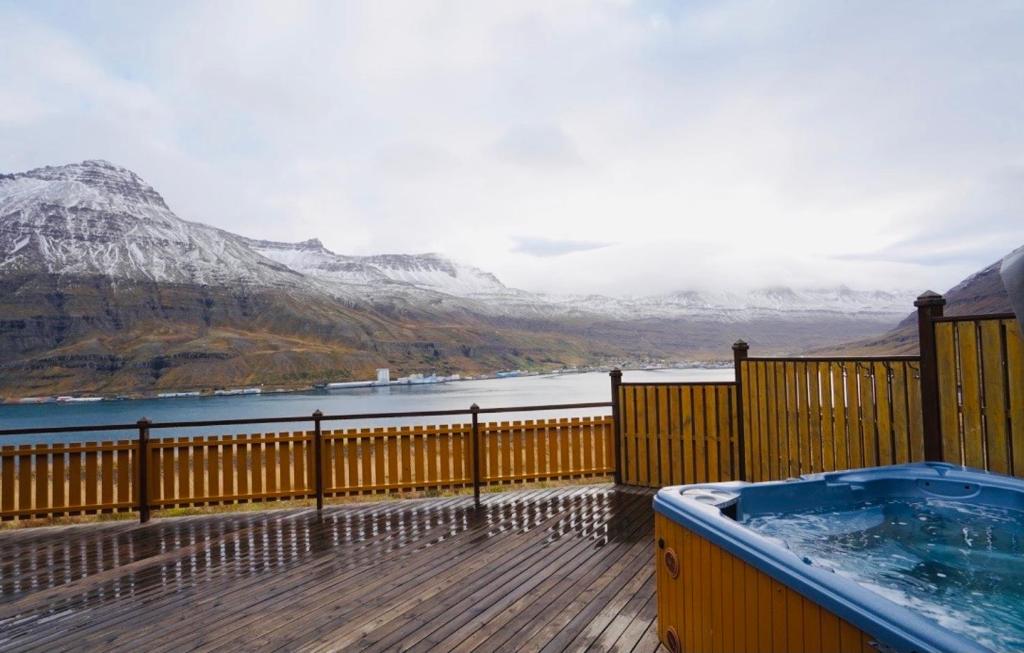 a hot tub on a deck with a view of the mountains at Langahlid Cottages & Hot Tubs in Seyðisfjörður