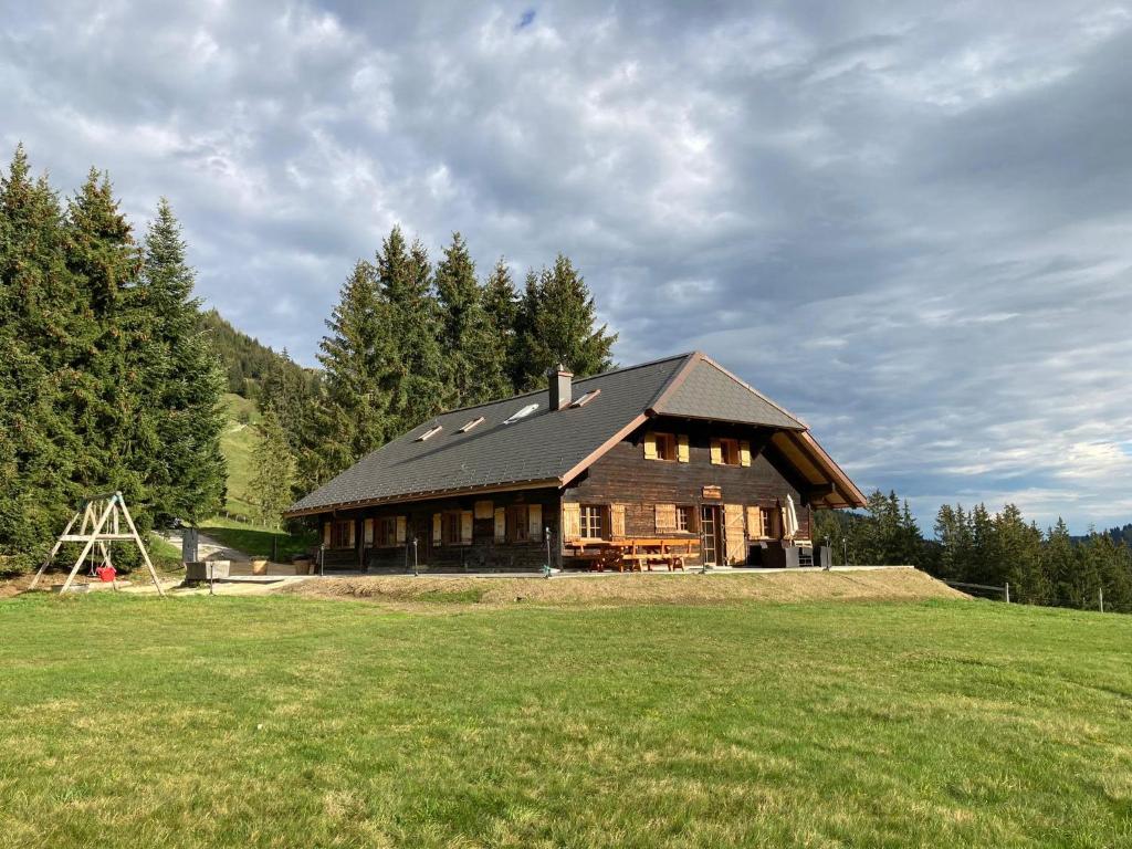 a large wooden house in a field with trees at Chalet Schwendli in Schwarzsee