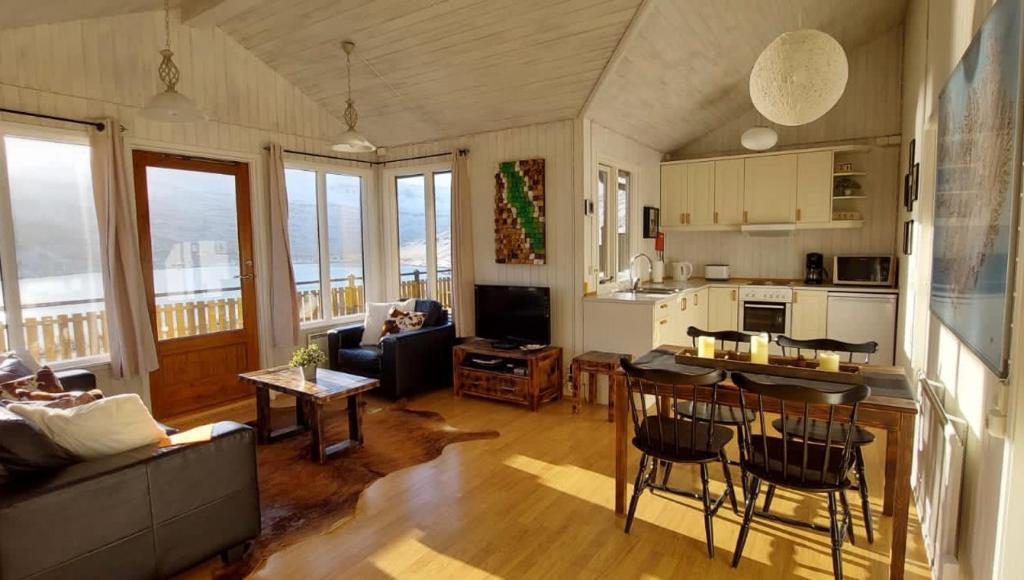 a living room with a couch and a table and a kitchen at Langahlid Cottages & Hot Tubs in Seyðisfjörður