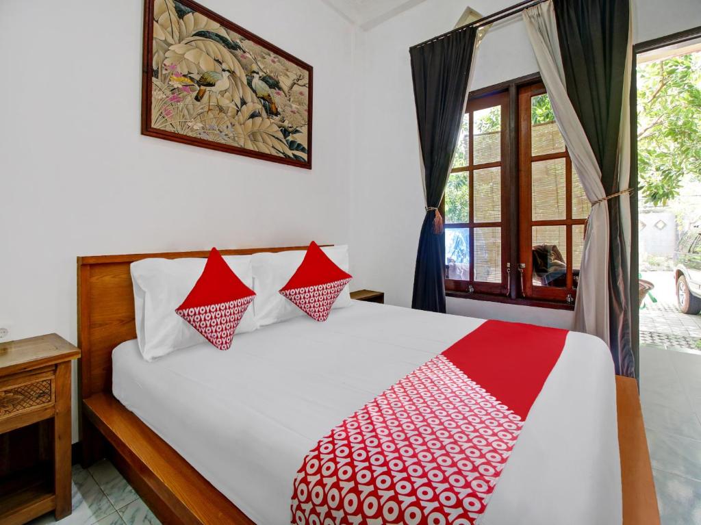 um quarto com uma cama com um edredão vermelho e branco em SUPER OYO 90672 ADHYA GUEST HOUSE LOMBOK em Tjakranegara