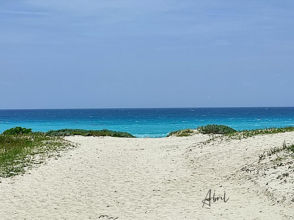 una playa de arena con el océano en el fondo en Tu Casa en el Caribe, en Cancún