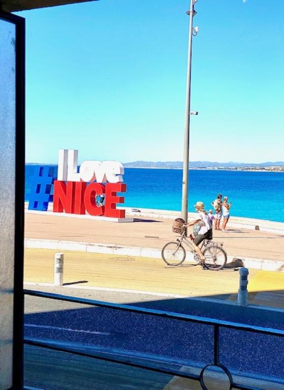 une personne voyageant à vélo sur un trottoir à côté de l'océan dans l'établissement LE ROCAMARE -Superb-Atypical Sea view-A.C-WIFI, à Nice