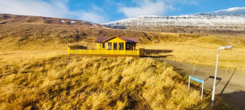 a yellow house on the side of a hill at Langahlid Cottages & Hot Tubs in Seyðisfjörður
