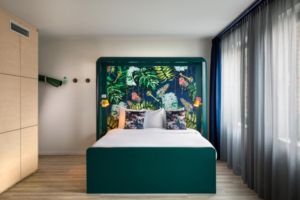 a bedroom with a large bed with a green headboard at B&B HOTEL Brussels Centre Louise in Brussels