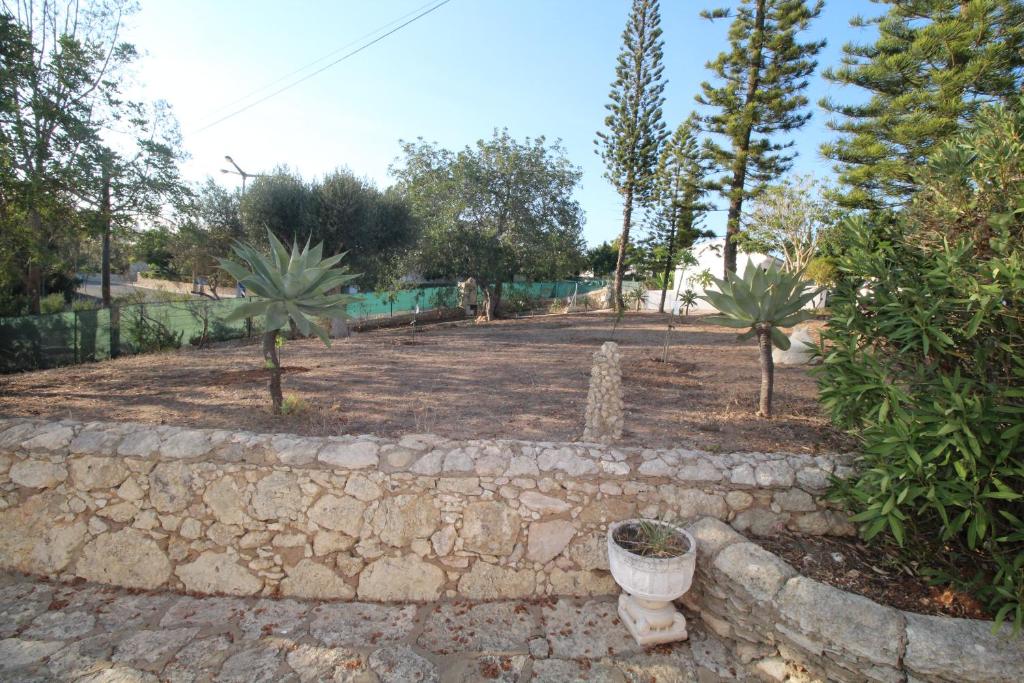 a garden with palm trees and a stone wall at Casa do Milho in Carvoeiro