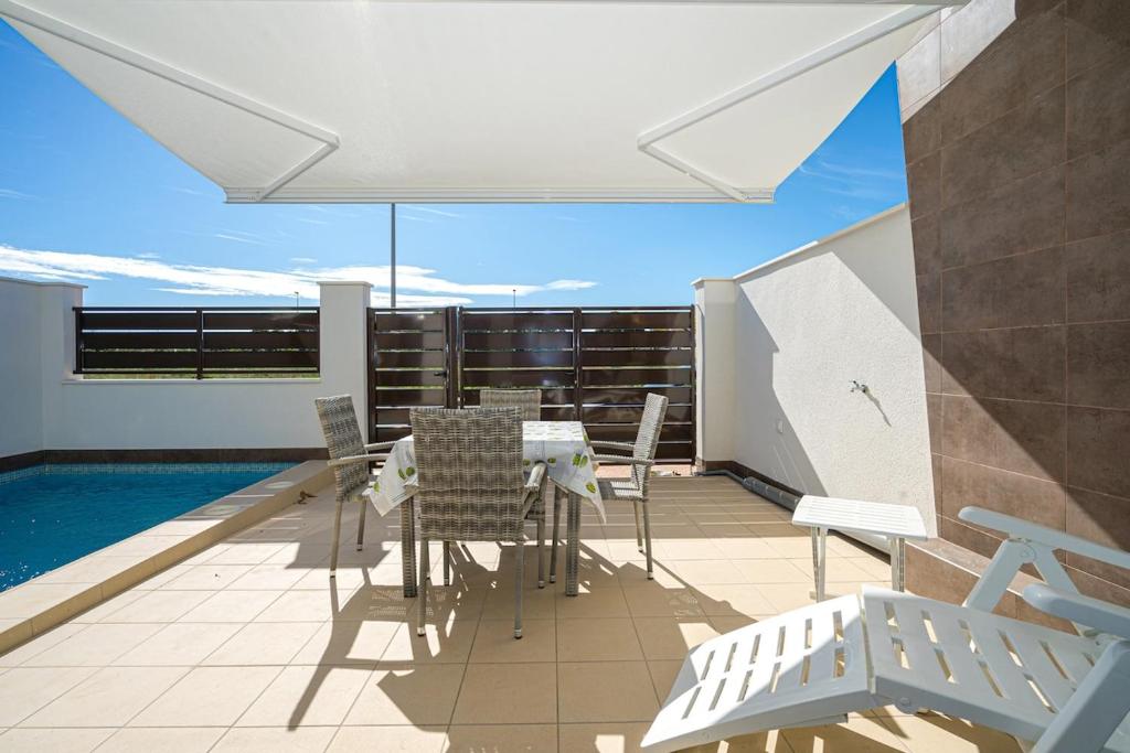 a balcony with a table and chairs and a pool at Stachera in San Pedro del Pinatar