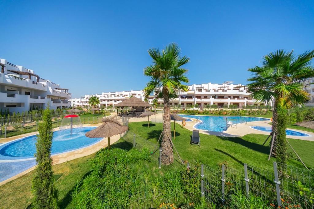 un complexe avec une piscine et des palmiers dans l'établissement Verde, à San Juan de los Terreros