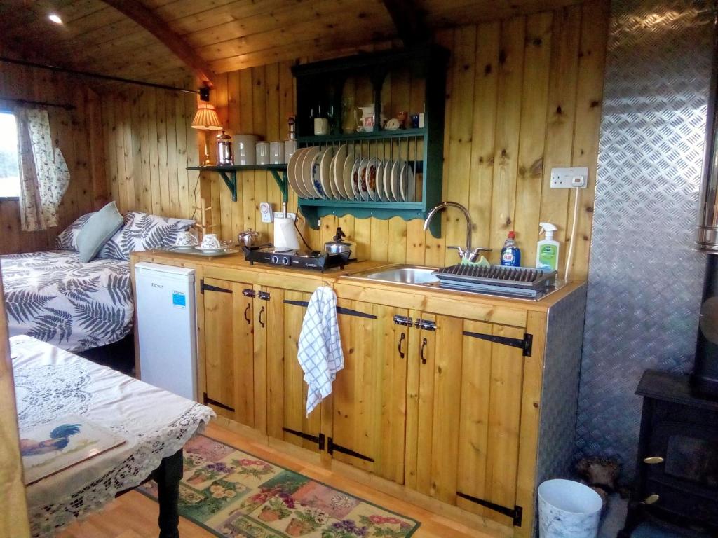 a kitchen with wooden cabinets and a sink in a room at Lower Haven Shepherds Hut in Bath