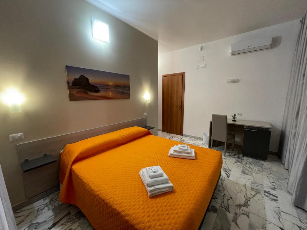 ein Schlafzimmer mit einem orangenen Bett mit zwei Handtüchern darauf in der Unterkunft B&B CENTRALE in Gela