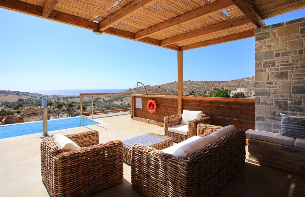 d'une terrasse avec des chaises en osier et une vue sur la piscine. dans l'établissement Phaestias Terra Villas, à Kalamaki