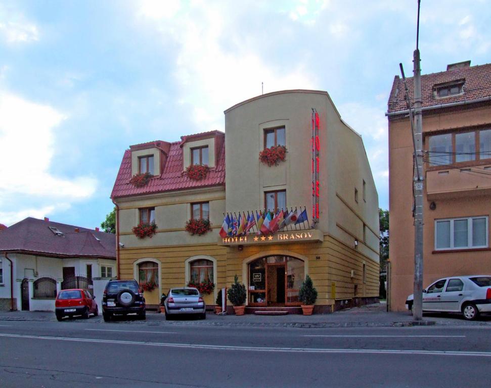 een gebouw waar auto's voor geparkeerd staan bij Hotel Brasov in Braşov