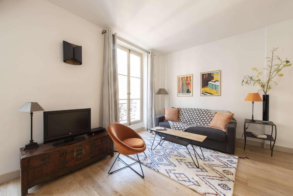 - un salon avec un canapé et une télévision dans l'établissement Cada Vez, à Paris