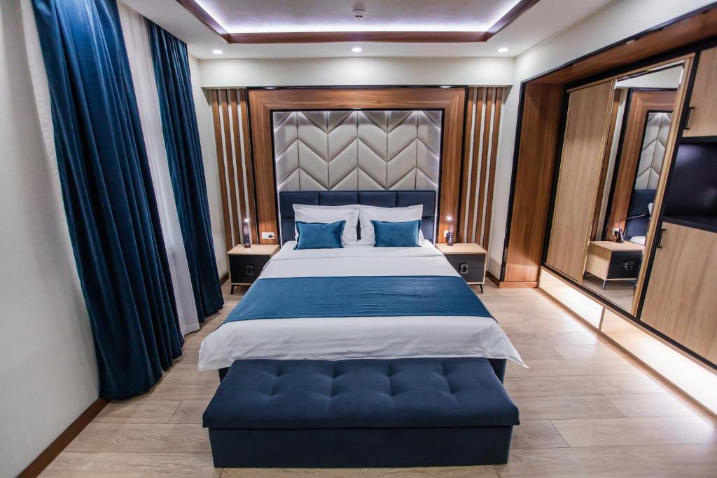 a bedroom with a large bed with blue pillows at Art Deluxe Hotel in Tashkent