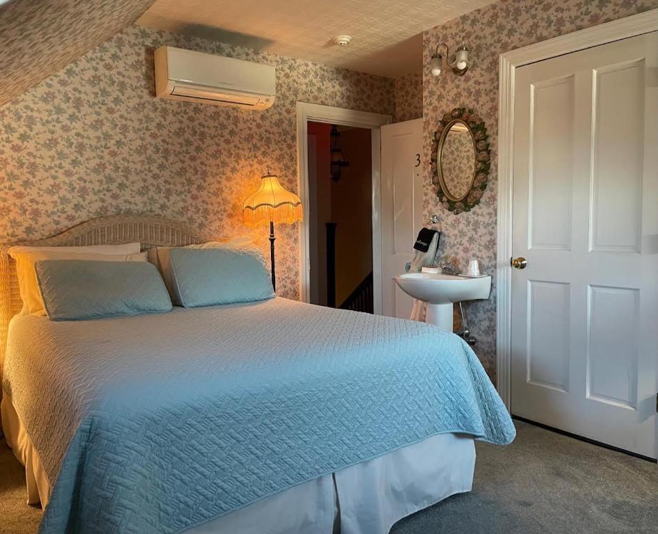 a bedroom with a blue bed and a sink at Luther Ogden Inn in Cape May