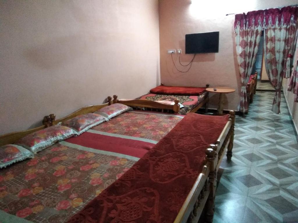 a room with three beds and a tv on the wall at MANIIS HOMESTAY in Vālpārai