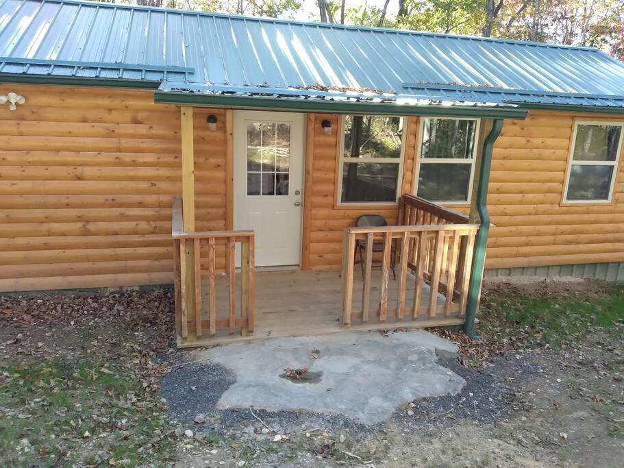 eine Hütte mit einer Veranda und einer weißen Tür in der Unterkunft Cabin with a tree house on a buffalo farm . in Marshall