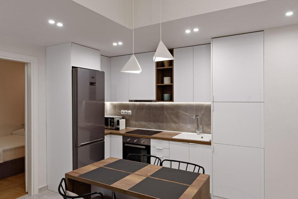 een keuken met witte kasten en een tafel met stoelen bij Blu & Marrone Suites-free parking in Thessaloniki