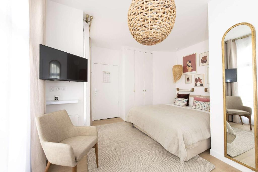 une chambre avec un lit, une chaise et un miroir dans l'établissement Candide, à Paris