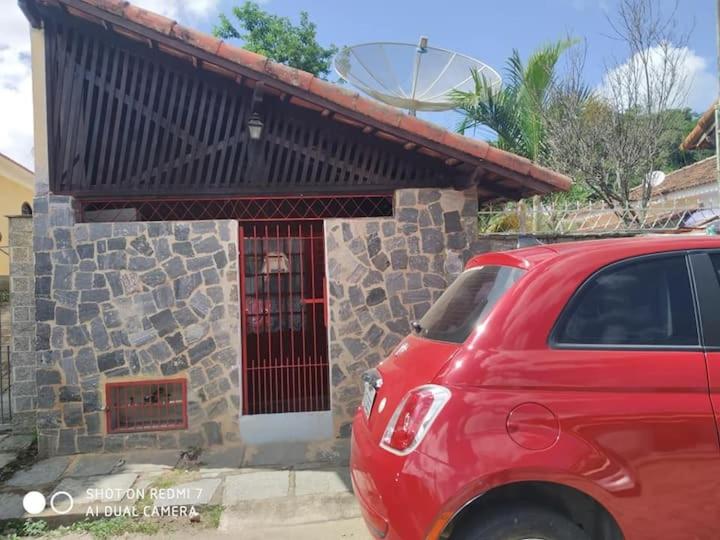 un coche rojo estacionado frente a un edificio en Casinha Aconchegante no 3° Melhor Clima do Mundo., en Miguel Pereira