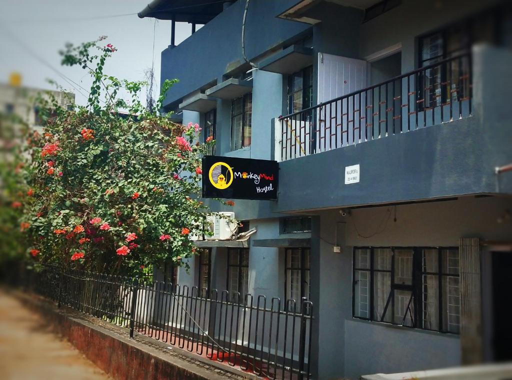 a blue building with flowers and a sign on it at Monkey Mind Hostel in Madgaon