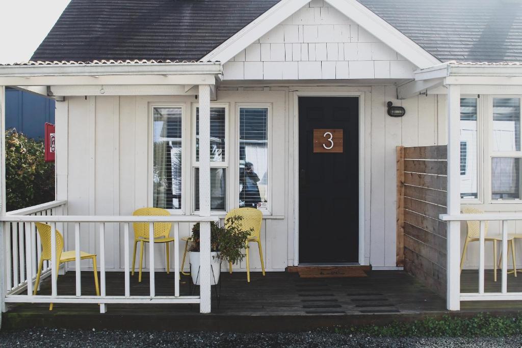 a white house with yellow chairs and a black door at Boardwalk Cottages in Long Beach