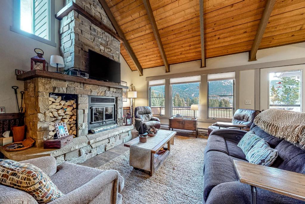 a living room with a stone fireplace and a couch at Glacier & Ducks Unlimited in Big Sky