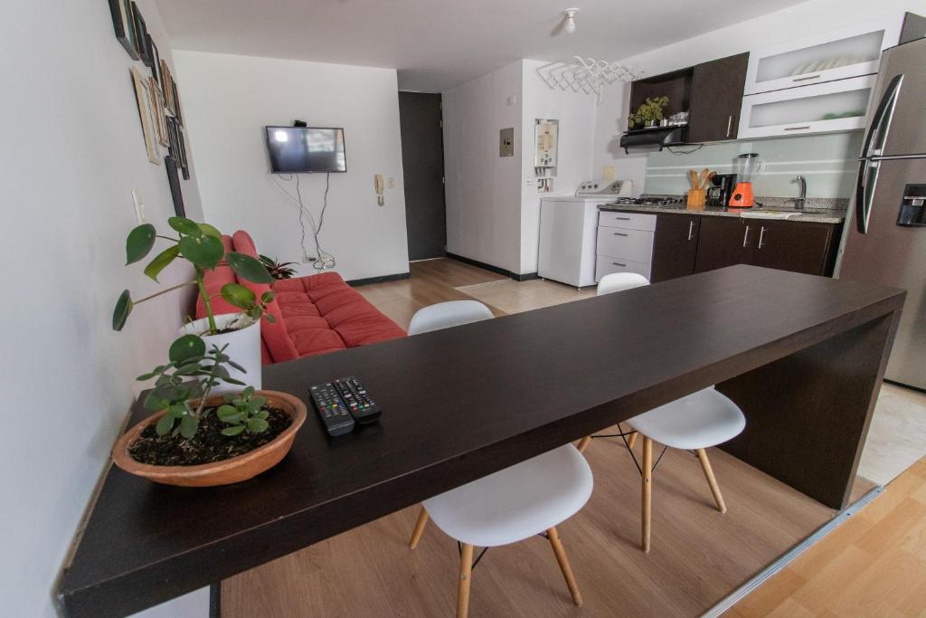cocina y sala de estar con mesa negra y sillas en Milán, Acogedor apto en Zona Rosa con Balcón, en Manizales