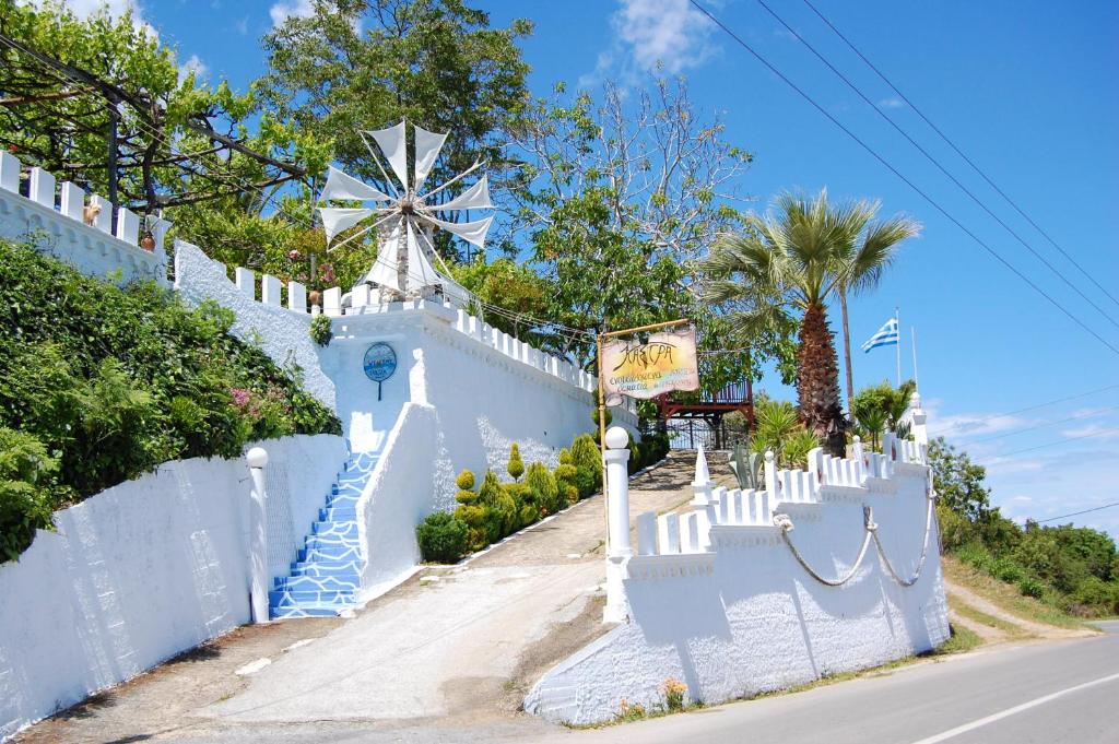 a white fence with a windmill on the side of a road at Kastra in Velika