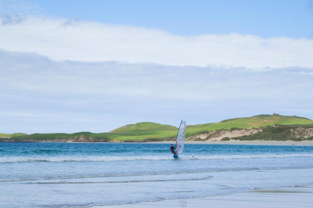 a person is windsurfing in the water on the beach at Durness Youth Hostel in Durness