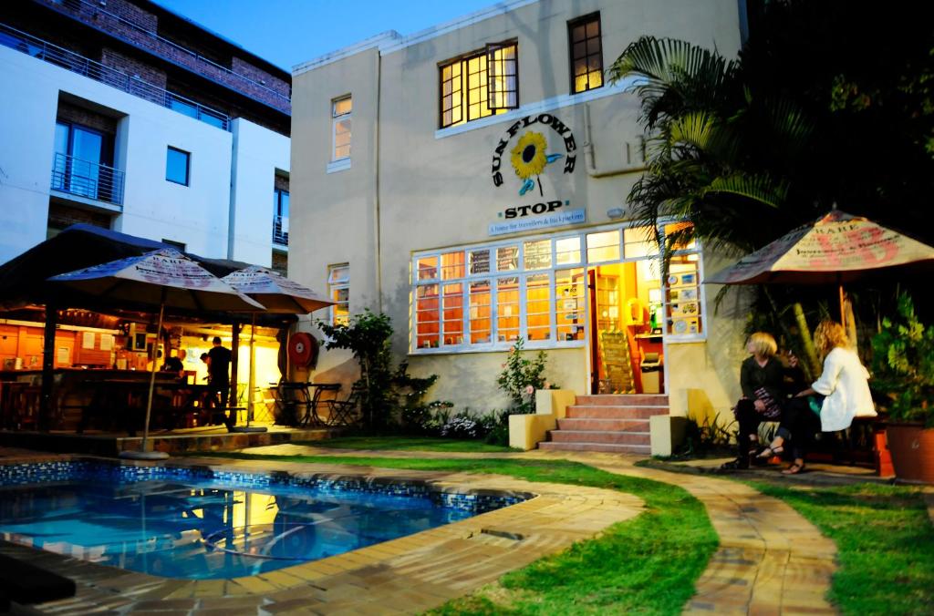 un grupo de personas sentadas frente a un edificio en A Sunflower Stop Backpackers, en Ciudad del Cabo