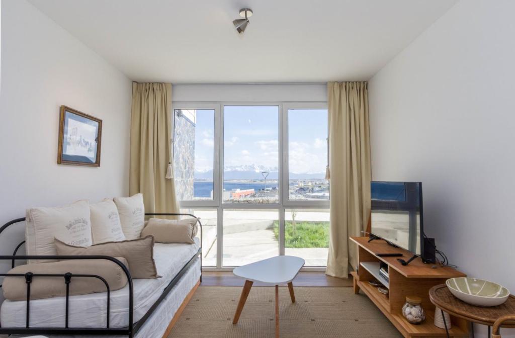 a living room with a couch and a large window at Edificio Miradores del Beagle in Ushuaia