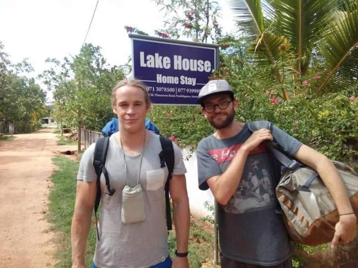dos hombres parados frente a un letrero de la casa del lago en Lake House Homestay, en Anuradhapura