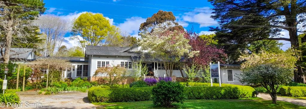 a house with trees and bushes in front of it at The Bundanoon Guest House in Bundanoon