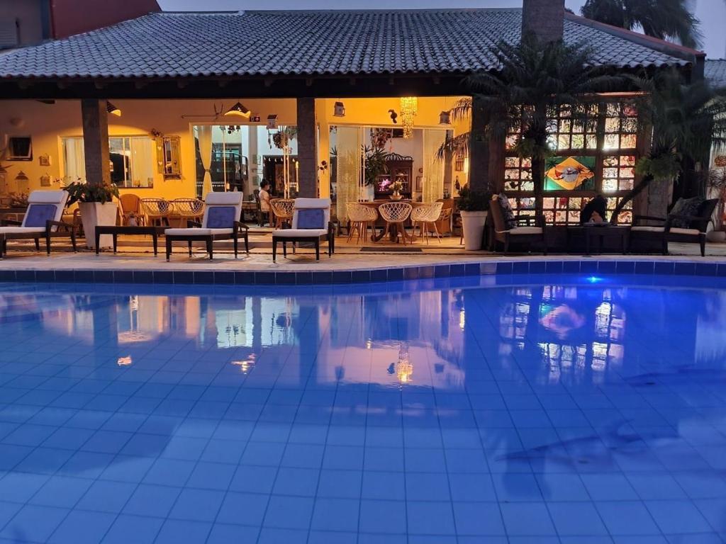 a large swimming pool with chairs and a house at Pousada Villa Caiobá in Matinhos