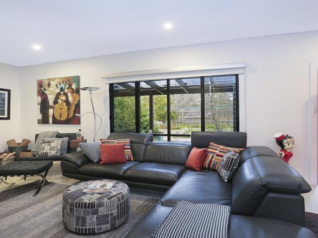 a living room with a black leather couch at Lovett in Mittagong