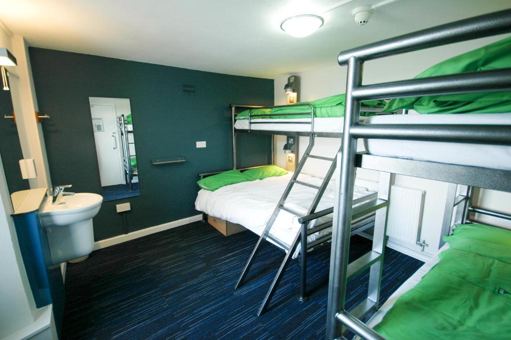 a room with a bunk bed and a bathroom with a sink at YHA Poppit Sands in Cardigan