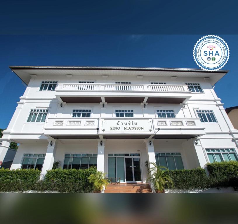 a white building with a sign on top of it at Sino Mansion in Ranong