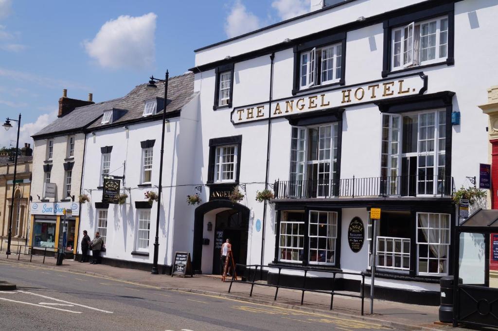 a white building on the corner of a street at The Angel Hotel in Coleford