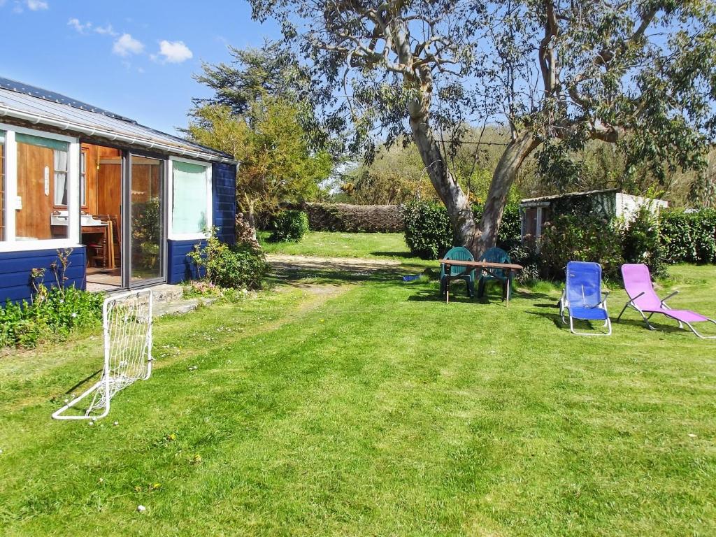 un patio con 2 sillas, una mesa y un árbol en Maison d'une chambre a Tredrez Locquemeau a 800 m de la plage avec jardin amenage et wifi, en Coat-Tredrez