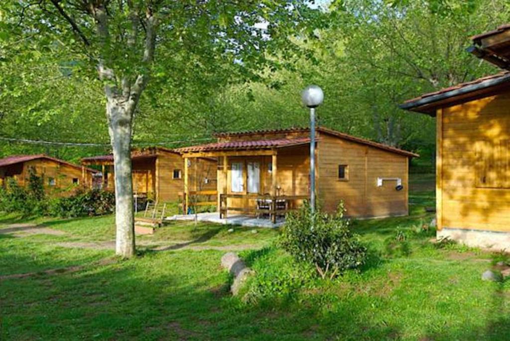a log cabin in a yard with a tree at Camping La Vall d'Hostoles in Sant Feliu de Pallerols