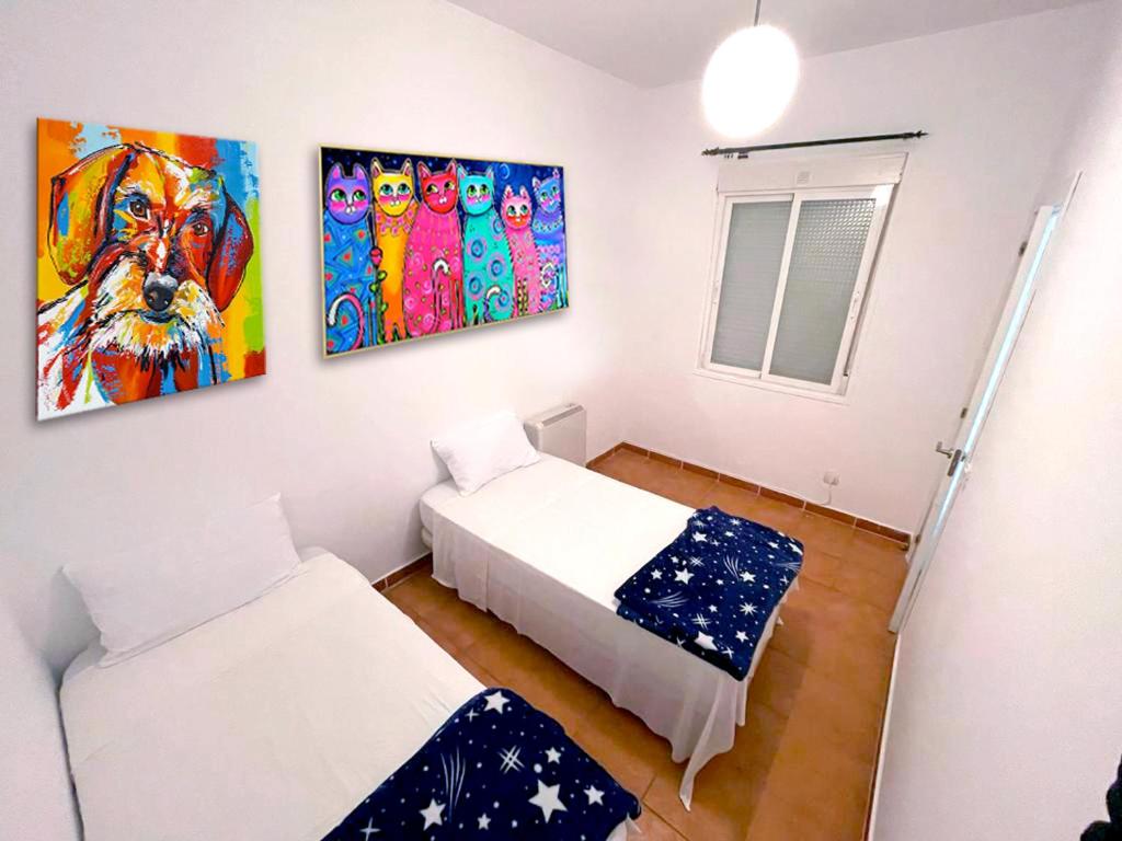 Habitación con 2 camas y pinturas en la pared. en Don Quijote APARTAMENTS TPH Madrid, en Madrid