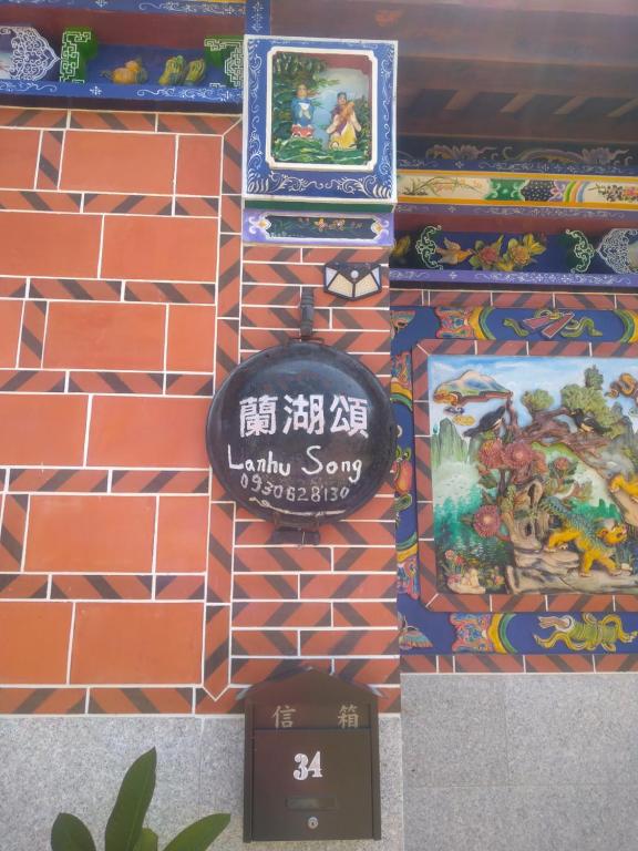 uma parede com sinais numa parede de tijolos em Lanhu Song B&B em Jinhu