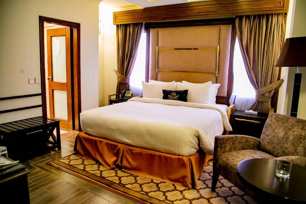 a hotel room with a large bed and a chair at Saffron D'or Hotels in Lahore