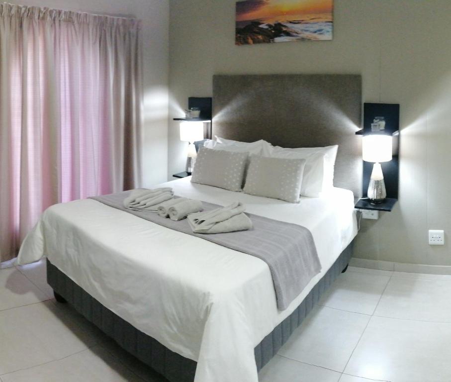 1 dormitorio con 1 cama grande y 2 toallas. en Meadowbrook Guesthouse, en Pretoria